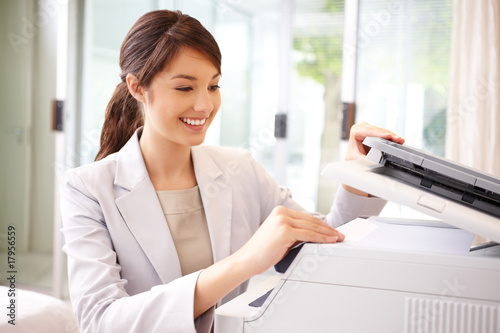 Cute young business woman making photocopies
