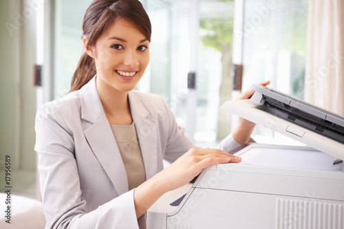 Photo: Happy business woman working on the photo copy machine Happy business woman working on the photo copy machine