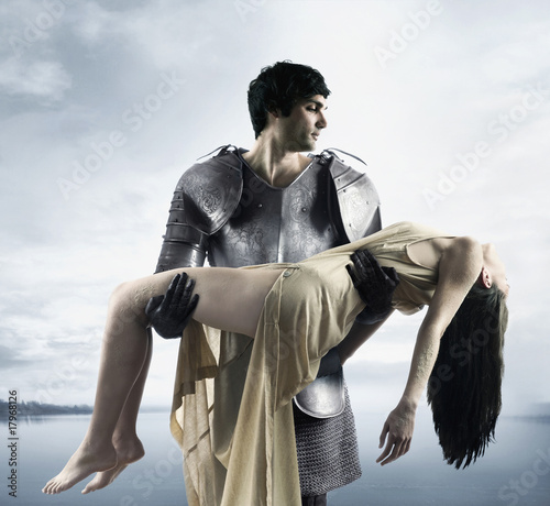 Photo: Mixed Race man in suit of armor carrying woman Mixed Race man in suit of armor carrying woman
