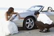 Hispanic newlyweds changing car tire
