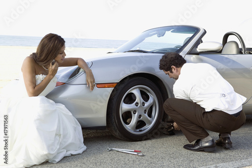 Foto: Hispanic newlyweds changing car tire Hispanic newlyweds changing car tire