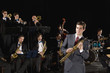 Man holding clarinet in front of orchestra