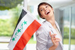 Cute woman laughing while holding an Iraqi flag , looking away