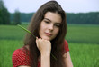 Beautiful girl шт red dress in green field with bunch of wheat