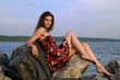 Beautiful girl sit on rock on sea coast