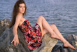 Beautiful girl sit on rock on sea coast