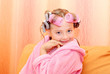 A child with an unusual hairdo sitting on an orange sofa.