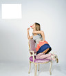 girl standing on knees on chair sucking lollipop, reading sign