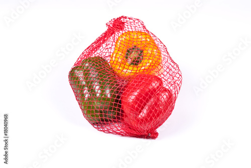 yellow green and red peppers in the red string bag