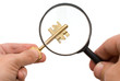 Two hands with magnifier and key over white Two hands with magnifier and key over white