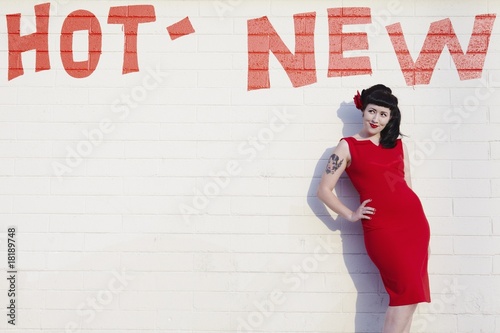 Photo: Retro woman in red dress posing against a brick wall Retro woman in red dress posing against a brick wall