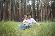 Man and girl sit in woodland clearing