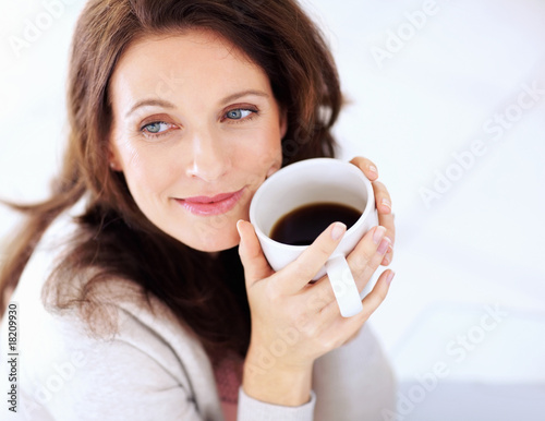 Photo: Happy woman having coffee looking away in thought Happy woman having coffee looking away in thought