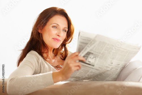 Photo: Pretty happy woman reading a newspaper Pretty happy woman reading a newspaper