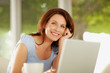 Foto: Portrait of a mature woman with a laptop and coffee cup in front Portrait of a mature woman with a laptop and coffee cup in front