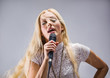 beautiful blond young woman singing into a microphone