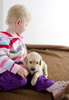 little girl playing with puppy of golden retriever