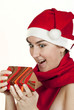 The beautiful girl smiles in a New Year's cap hoding a present The beautiful girl smiles in a New Year's cap hoding a present
