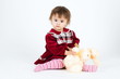Little girl in red dress sitting with toy bear