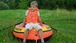 boy dressed in life jacket dragging inflatable rubber