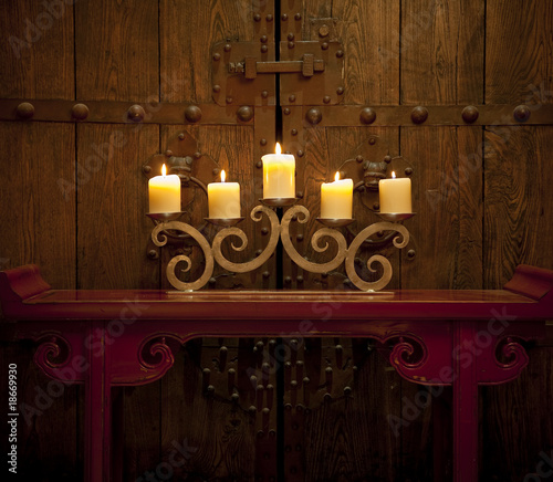 Photo: Candles burning on table in front of old rustic door Candles burning on table in front of old rustic door
