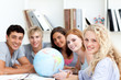 Photo: Smiling teenagers in a library working with a terrestrial globe Smiling teenagers in a library working with a terrestrial globe