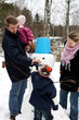 Family making snowman in winter park