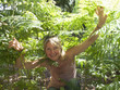 Smiling woman crouching among plants in forest