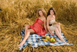 Two beautiful slavonic girls on picnic in wheat field