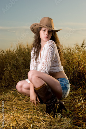 Photo: Beautiful slavonic girl in cowboy clothes pose in wheat field Beautiful slavonic girl in cowboy clothes pose in wheat field