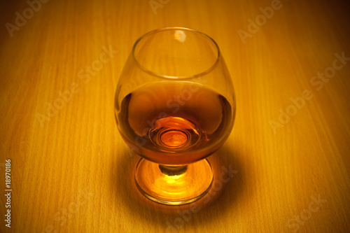 Photo: glass of cognac close-up on wooden background glass of cognac close-up on wooden background