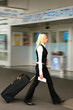Blonde Frau auf dem Weg zum Abflug am Flughafen