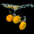 Fresh tangerines dropped into water with bubbles on black