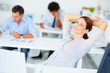 Relaxed newspaper editor with colleagues working at the back