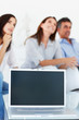 Opened laptop with business colleagues in the background