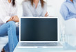 Closeup of a laptop on a table, people at the background