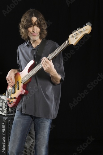 Photo: Mid adult man stands playing an electric guitar Mid adult man stands playing an electric guitar