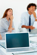 Opened laptop with business colleagues in the background