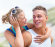 Happy young couple playing piggyback by the sea