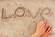 Human hand in scripting the word 'love' on the sand at the beach