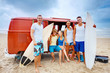 Foto: Group of teenagers at a beach picnic, guy with their surf board Group of teenagers at a beach picnic, guy with their surf board