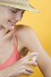 A Young Woman Spraying Suntan Lotion On Her Arm