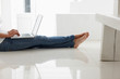 Low section of a female sitting on floor using a laptop