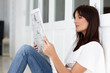 Cute female reading a newspaper by the door