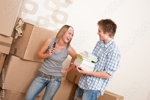 Moving house: Young couple with box in new home Moving house: Young couple with box in new home