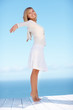 Happy young female on her tip toes against the blue sky