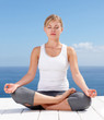 Young female meditating on a porch against the sky
