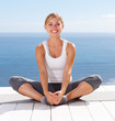 Happy young female practicing yoga outdoors , legs together