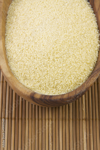 Photo: Wooden bowl with uncooked couscous. Wooden bowl with uncooked couscous.