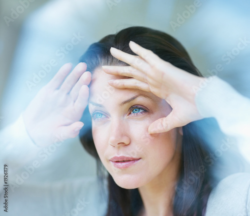 Foto: Anticipation - Young female looking outside through a glass wall Anticipation - Young female looking outside through a glass wall